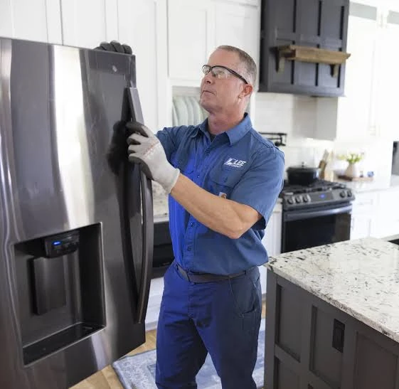 Technician inspecting a stainless steel refrigerator door
